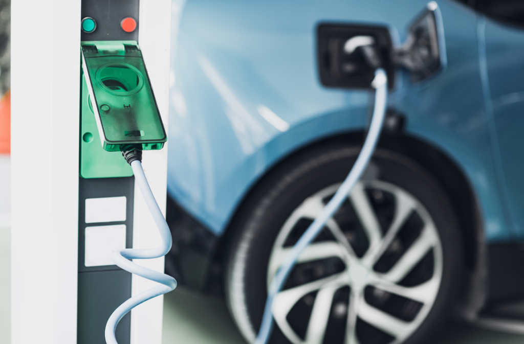 Blaues Elektrofahrzeug an einer Aufladestation - Steuern sparen mit einem Elektroauto